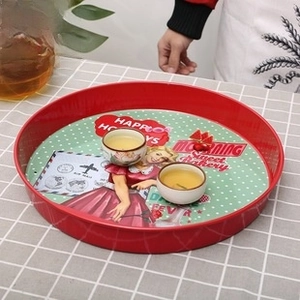 Close-up of vintage tin tray featuring green polka dots and Happy Holidays illustration
