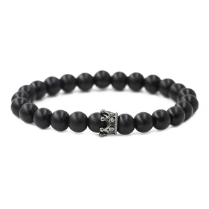 Detail of matte black stone bead bracelet with a micro-pave crown charm and copper beads