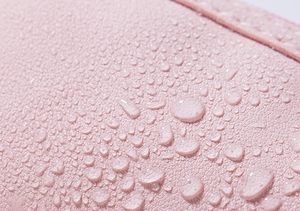 Macro shot of pink waterproof fabric texture with clear water droplets on the surface