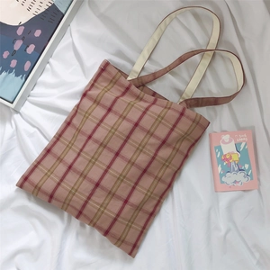 Detailed close-up of pink and brown checkered canvas tote bag on soft white fabric