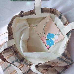 Macro view of plaid canvas tote bag showing interior lining and small pocket detail