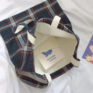 Detail view of plaid tote bag featuring thick inner lining and internal storage pocket