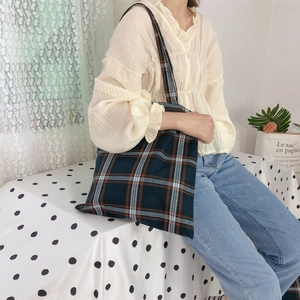 Close-up of thick plaid canvas tote bag in dark teal and orange on a soft home background