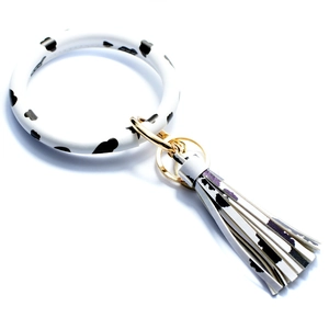 Close-up of stylish cow print silicone wristband keychain with matching tassel and gold hardware