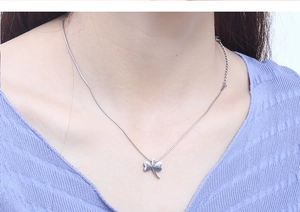 Close-up of a silver dragonfly pendant necklace on a model's neck with fine snake chain