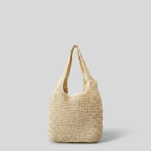 Handwoven beige straw tote bag for women on a rustic wooden table with forest background