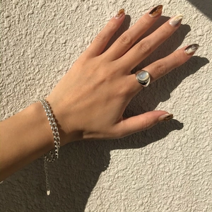 Detail of 925 silver beaded bracelets and oval white agate ring on hand