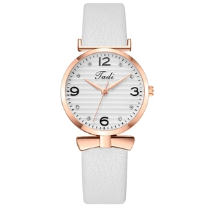 Détail de montre or rose avec bracelet en cuir blanc et nœud en cristaux