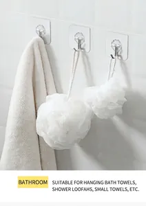 Strong transparent adhesive hooks on a white tile wall holding bathroom accessories