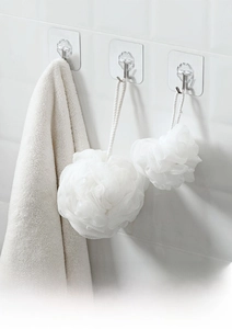 Strong transparent adhesive hooks on a white tile wall holding bathroom accessories