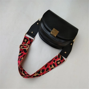 Close-up of leopard print wide strap and gold buckle on a black saddle bag