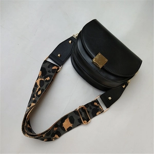 Detail of adjustable leopard print wide strap and gold hardware on black saddle bag