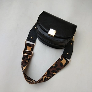 Macro detail of leopard print strap with gold rivets on a black leather saddle bag