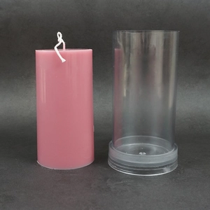 Macro view of transparent cylindrical candle mold with a pink wax pillar next to it