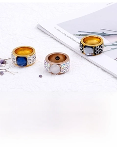 Macro shot of wide gold and rose gold rings with colorful gemstones and pavé crystals