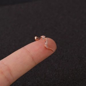 Rose gold snake cartilage earring with cubic zirconia studs held on a fingertip