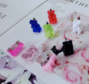 Detailed view of colorful gummy bear pins with metal back fasteners on a floral background