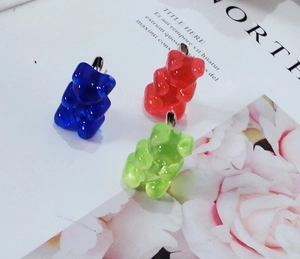 Close-up of translucent gummy bear charms in red, blue and green with metal hooks