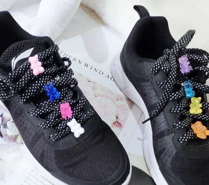 Close-up of colorful resin gummy bear charms attached to black sneaker laces as accessories