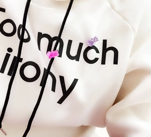 Close-up of hoodie chest featuring black text print and drawstrings with beads
