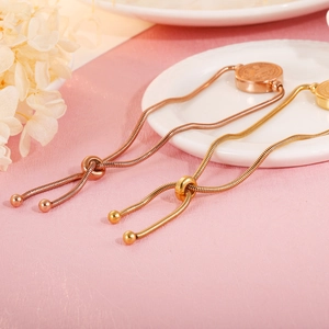 Detail of adjustable snake chain bracelet with round embossed pendant in gold finish