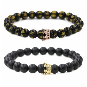 Close-up of beaded crown bracelets featuring matte and polished black onyx with gold charms