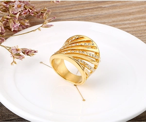 Detail of a gold hollow-out ring with white rhinestones on a white porcelain plate