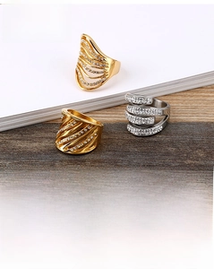 Detailed view of wide hollow wave rings with sparkling crystals in gold and silver