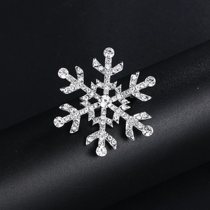 Broche flocon de neige argentée avec strass étincelants et perles sur support noir