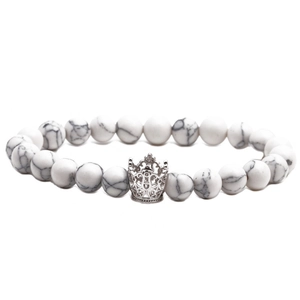 Detailed view of white turquoise beads and a silver crown pendant on a beaded bracelet