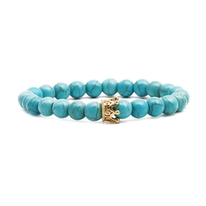 Bohemian turquoise bead bracelet with gold crown charm and white zircon inlays on white backdrop