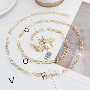 Elegant gold metal bee waist chain with white pearls on a minimalist background