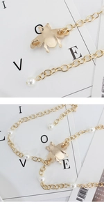 Detail of gold metal waist chain featuring a vintage bee pendant and faux pearls accents