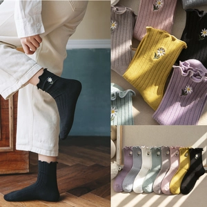 Detail of floral embroidered cotton socks featuring cute daisy patterns and wavy cuffs