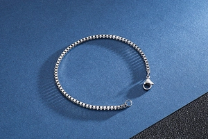 Detailed close-up of a silver stainless steel box chain bracelet with a lobster clasp