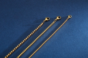 Detailed close-up of three gold stainless steel box chains with secure lobster clasps