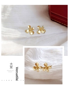 Close-up of golden gardenia flower earrings with matte texture and 3D petal design