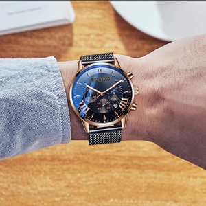Detailed view of Roman numeral watch with blue sunray dial and black mesh strap on wrist