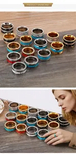 Multiple wide stainless steel rings with turquoise and rhinestones on a wooden background