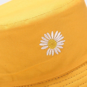 Close-up of yellow cotton bucket hat with detailed daisy embroidery and twill texture