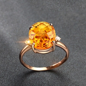 Close-up of an oval yellow gemstone ring in rose gold with small diamond accents