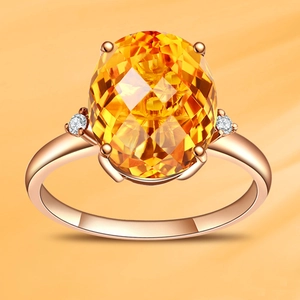 Macro shot of rose gold ring featuring a large oval yellow gemstone with side accents
