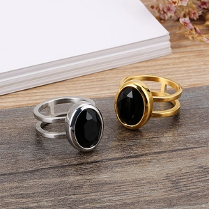 Gold and silver stainless steel rings with oval black gemstones on dark wood surface
