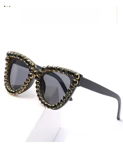 Detailed close-up of cat-eye sunglasses with gold-clawed black rhinestones and grey lenses