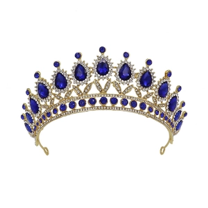 Detail shot of golden crown with blue teardrop rhinestones on white background