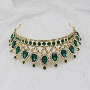 Detail of golden bridal crown with emerald water-drop stones on lace background