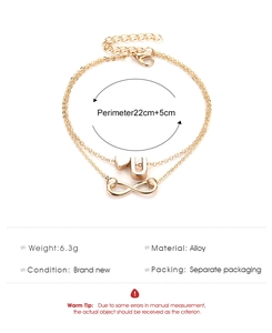 Detail of gold double-layer anklet with heart, U-letter and infinity pendants