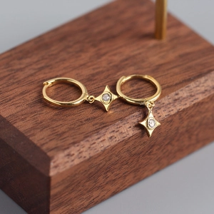 Elegant gold S925 silver star hoop earrings with diamond-set charms on wooden display