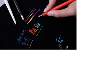 Close-up of dual-tip scratching tool for art showing fine and thick lines on black paper