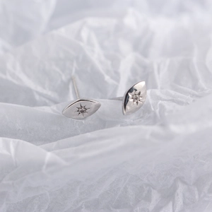Macro view of minimalist S925 sterling silver eye-shaped studs with eight-pointed star detail